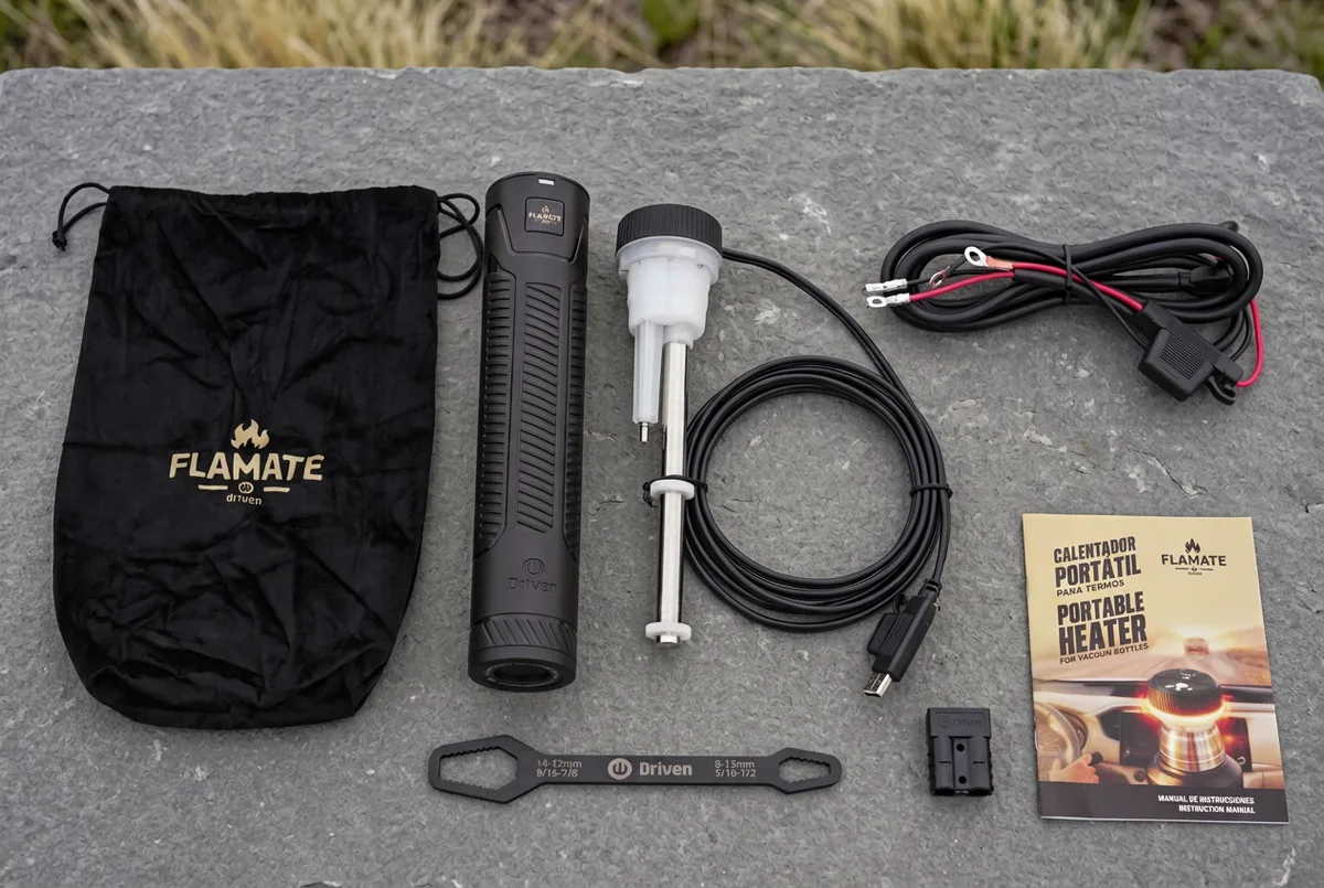 Flamate con bolso, protector, cables, llave y manual sobre una superficie de piedra